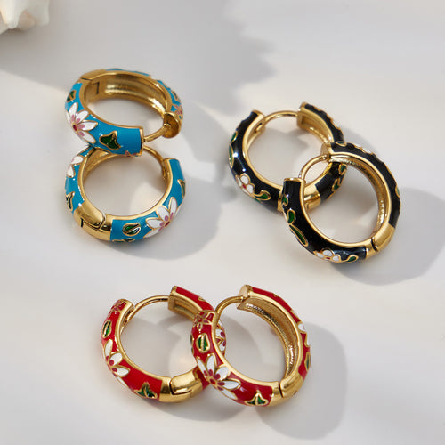 Black red and blue enamel flower huggie hoops on white surface