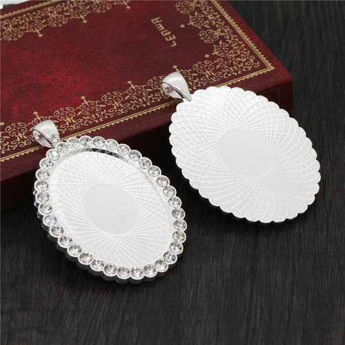 Oval cabochon pendant tray bordered with rhinestones in a close view showing the front and back