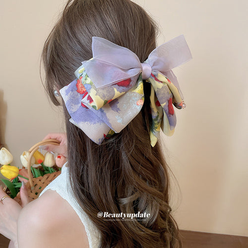 Purple organza floral bow claw worn in long brown hair from behind