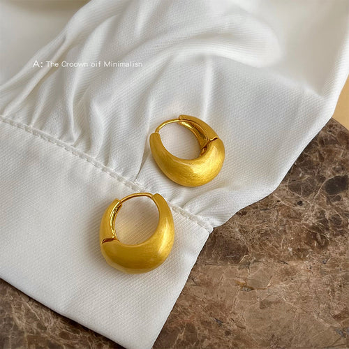 Gold matte chunky huggie hoops on white fabric sleeve