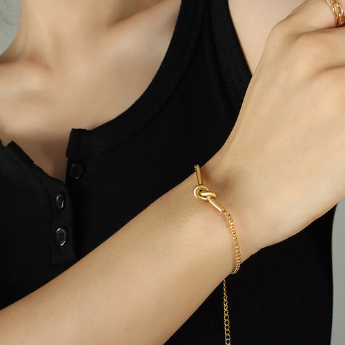 Gold lucky knot bar bead chain bracelet worn on wrist black top