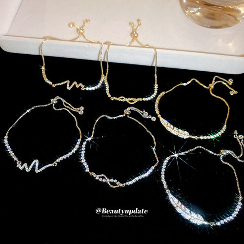 Six gold and silver adjustable rhinestone motif bracelets laid on black velvet