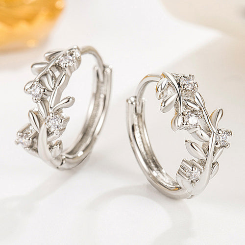 Angled detail view of silver tone leaf vine hoop earrings with clear stone accents