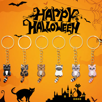 Six cartoon cat keychains lined up on orange Halloween backdrop