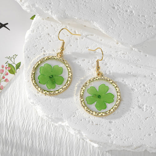 Green pressed flower round resin drop earrings with gold frames on white stone