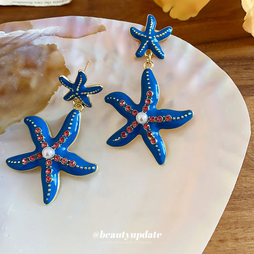 Layered blue starfish forms accented with small red crystals shown in a styled view.