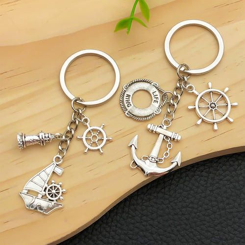 Alternate arrangement of the antique silver nautical anchor and sailboat keychain showing its hardware and charm details
