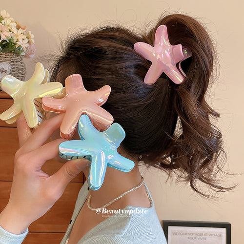 Woman wearing pink starfish claw with three other colors held in hand