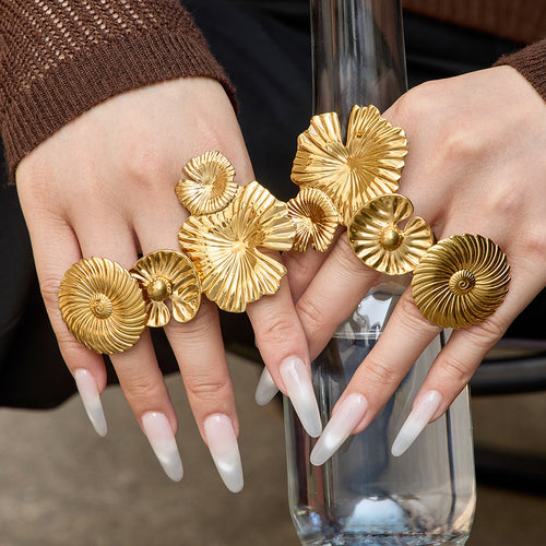 Styled hand view of textured disc and flower statement rings in main image 1.