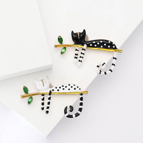 Black and white enamel cat brooches on white blocks