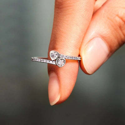 Silver double heart CZ bypass ring worn on fingertip outdoor light