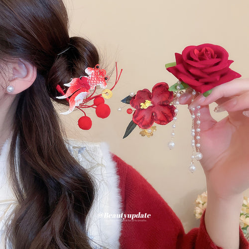 Red goldfish hair pin worn in bun while rose and flower clips are held