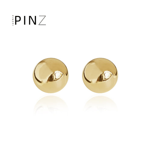 Pair of gold polished dome ball stud earrings on white reflection