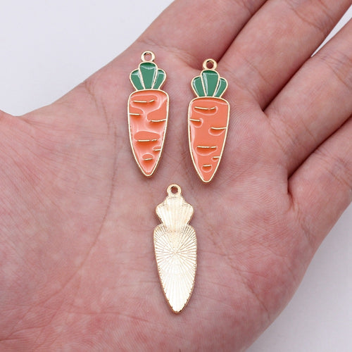 Long pink carrot enamel charm shown on a hand for scale
