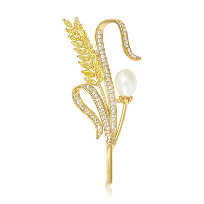 Front view of golden wheat-ear brooch with crystal curves and pearl-like bud against a white background.