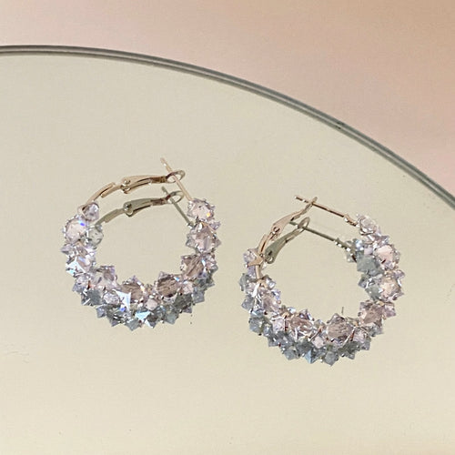Small hoops covered with clear floral and leaf-shaped crystals displayed in a close product arrangement.