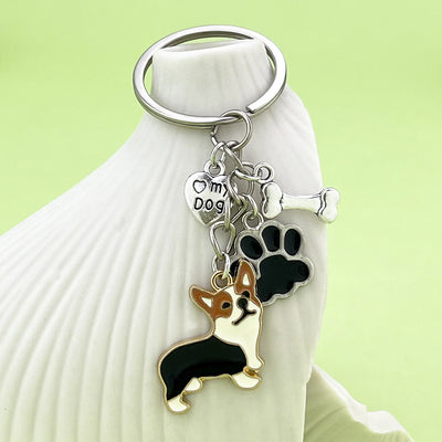 Black corgi keychain with paw, bone and heart charms hanging from a white ceramic object.