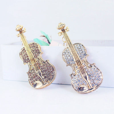 Two gold-tone violin ornaments display clear and light coffee rhinestone fronts.
