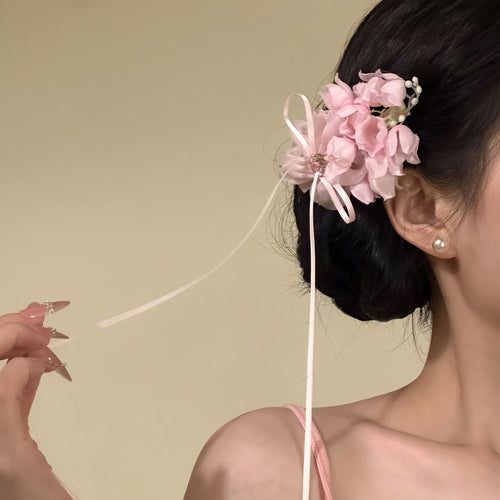 Pink chiffon flower duckbill clip with trailing ribbon on dark bun