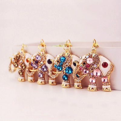 Four gold-tone elephant keychains with brown, purple, blue, and pink stones arranged in a row.