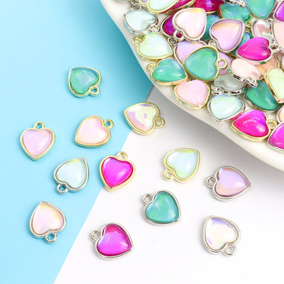 Assorted iridescent heart charms arranged beside a tray on white