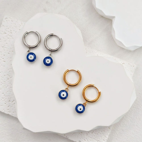 Gold and silver evil eye drop huggies displayed on white stone tray