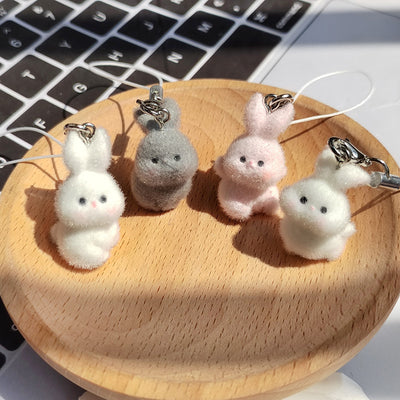 Four flocked bunny phone strap charms gray pink and white on wooden dish