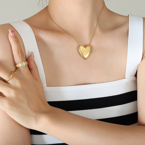 Gold puffy heart pendant worn on model with striped top