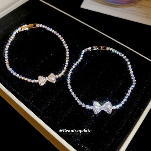 Gold and silver pave bow bracelets open on black velvet tray