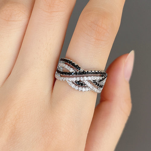 Black white crystal woven ring worn on finger against grey background