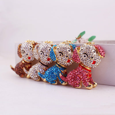 Four seated rhinestone dog charms in brown, white, blue, and pink.