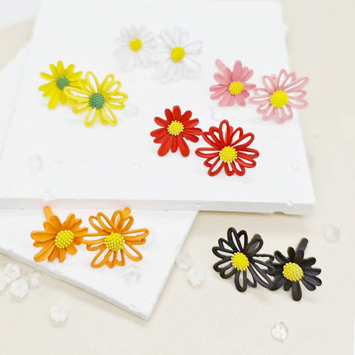 Six pairs of matte daisy flower stud earrings in yellow white pink red orange and black