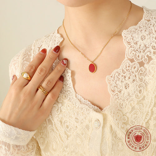 Gold red oval pendant close on lace top with rings and copyright seal