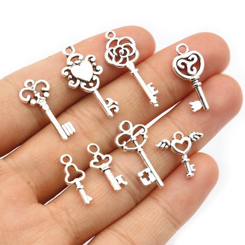 Assorted assorted vintage key charms in an antique silver tone arranged together on a plain background