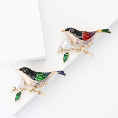 Grouped view of enamel Bird on Pearl Branch Brooch in Green or Red Wings arranged together.