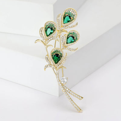Green Crystal Peacock Feather Brooch with Gold Tone Stem front view on a light background
