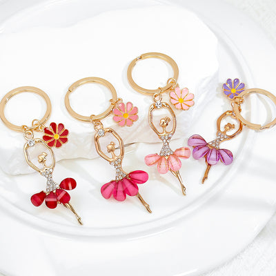 Four rhinestone ballerina keychains in different skirt colors with daisy charms