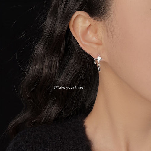 Silver-tone four-point-star clear-stone teardrop studs shown worn on an ear.