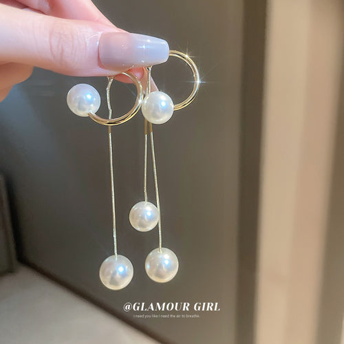 Styled close-up of gold tone pearl linear earrings