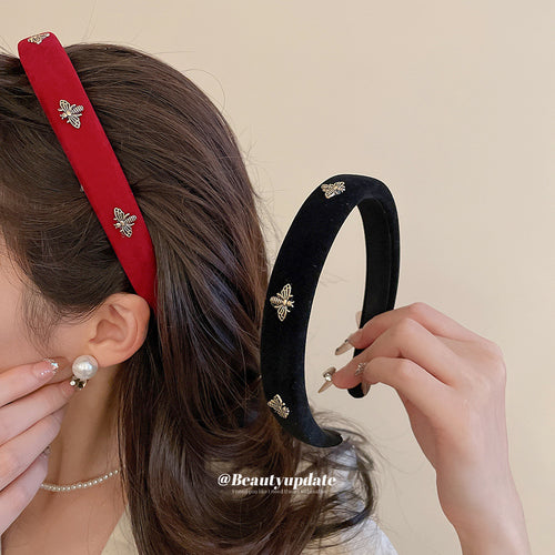 Red velvet bee headband worn; black bee headband held beside hair