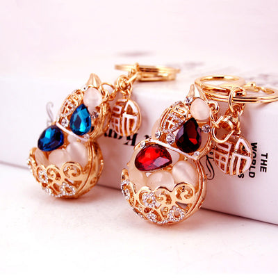Two gold-tone gourd keychains with red and blue faceted bead details.