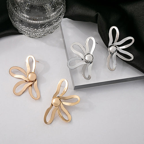 Gold and silver openwork flower stud earrings on white with black cloth