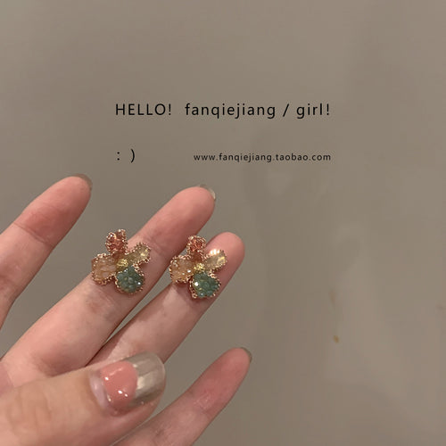 Unrelated flower studs held on fingers with brand watermark