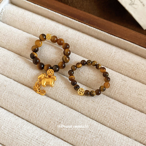 Coin-only and horse-charm tiger eye elastic rings in jewelry tray