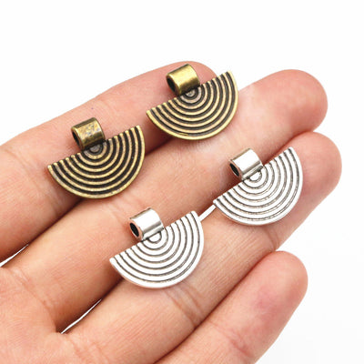 Overview of semicircular pendants formed by raised concentric arcs in antique bronze and silver tones