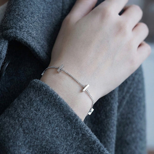 Steel bar station bracelet worn with grey coat sleeve