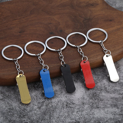 Five miniature skateboard keychains in gold, blue, black, red, and silver on a wooden surface.