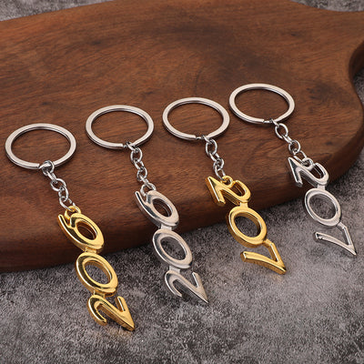 Four 206 and 207 pendant keychains in silver and gold tones displayed on wood.