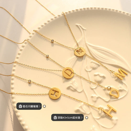 Gold M D H letter necklaces on ceramic plate with labels