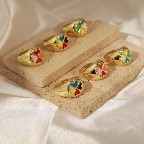 Assorted color gold clover heart rings displayed on stone blocks